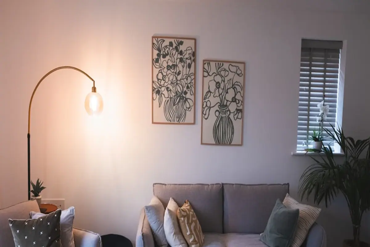 Clean editorial illustration of a custom-feeling rental living room with freestanding lighting, soft textiles, framed art, and no drilled hardware