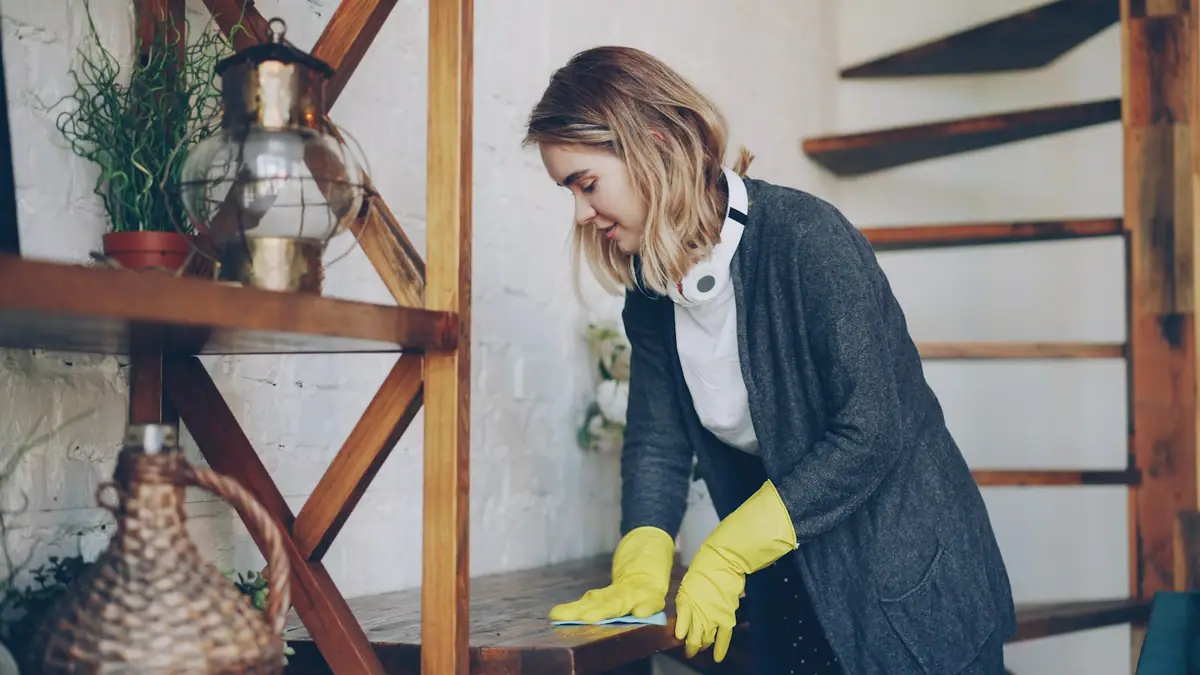 Person cleaning a home surface near a white wall with a cloth before a renter-friendly setup